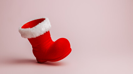 Santa Claus red boot on pastel pink background. Minimal Christmas eve or New Year celebration...