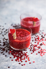 Fresh strawberry margarita or daiquiri cocktail with hearts over gray background, valentine day concepts