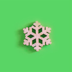 The above view on the handmade wooden snowflake on the green background, minimalism New Year or Christmas concept.