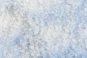 Obraz premium Close-up of fresh shiny snow on the ground on a sunny day, top view. Abstract natural textured background, copy space.