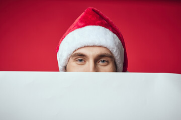 emotional man in a santa hat holding a banner holiday red background