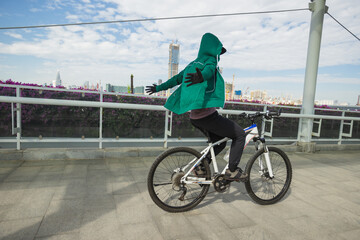 Woman riding bike without holding the handlebar no hands cycling at city on sunny day