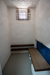 Empty loner prison cell with bars on the window