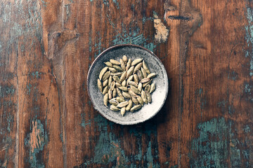 Green Cardamom Seeds on rustic wooden background. Top view. Close up. Copy space. 