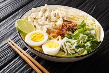 Soto Ayam is a classic chicken soup from Indonesia but also popular in Singapore and Malaysia close up in the plate on the table. Horizontal