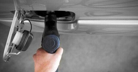 Gas station worker filling up bronze pickup truck tank (Top View). Closeup hand holding black gas...