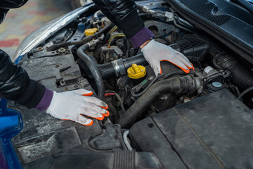 hands of the professional mechanic in special gloves carry out check of the car under a cowl