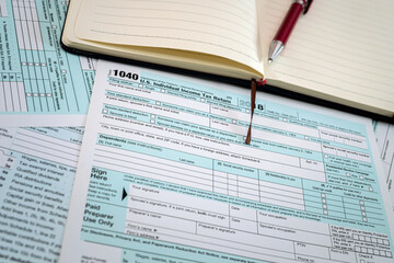 Obraz premium new US tax forms 1040 with a red pen and notebook are spread out on the table