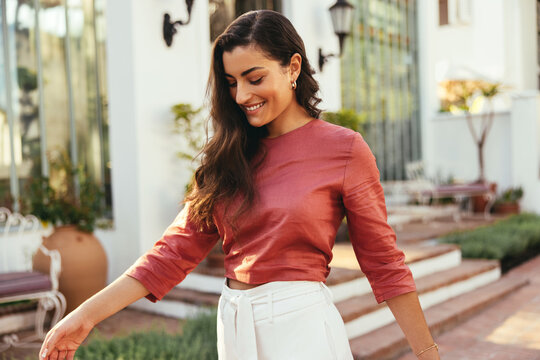 Happy young woman walking outside a luxury hotel