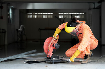 Electric circular saw tool in asian steelworker's hand. Metal grinding on steel spare part in workshop. Industrial worker cutting and welding metal.