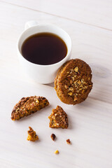 Cup of coffee with cookies on a white wooden table.