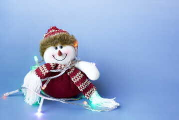 Smiling toy snowman in a Christmas garland.