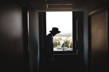 Silhouette of man in hat on background of window