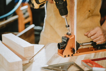 Carpenter use Cordless Drill and pocket hole jig or dowel jig ,Drive the screw on wooden plate,DIY maker and woodworking concept. selective focus