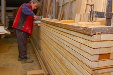 Squeezing with industrial metal f-clamp after gluing wooden profiles in workshop