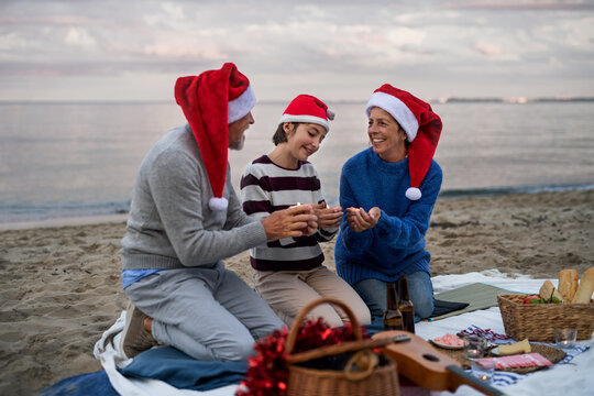 Senior couple with granddaugter celebrate New Year or Christmas and have picnic on beach.
