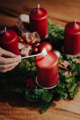 Lighting the first candle of Advent Wreath on the first Advent Sunday counting four weeks till Christmas. Old swiss tradition in December to celebrate Advent time. - obrazy, fototapety, plakaty