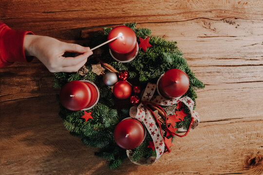 Lighting the first candle of Advent Wreath on the first Advent Sunday counting four weeks untill Christmas. Old swiss tradition in December to celebrate Advent time. View from above.