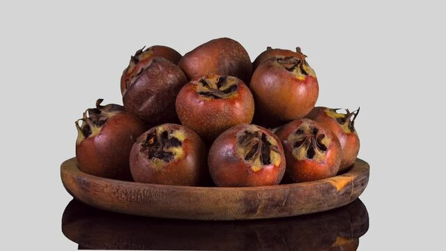 Whole ripe of organic Common Medlar rotate on white Background