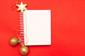 Gold Christmas balls and toys with empty blank note sheet on a red background