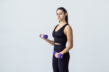 Young woman working out with dumbbells at home