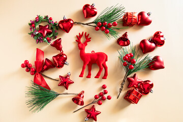 Red deer with other Christmas decoration in red tone, cones, tree ornament, hearts, stars on beige background.