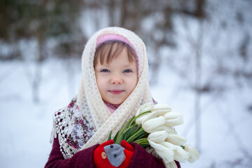 Close up winter portrait of adorable little caucasian girl with white tulips