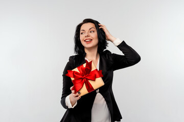 Fototapeta premium Beautiful smiling businesswoman holding gift box decorated with red ribbon. White background isolated studio portrait. Holidays, celebration and lifestyle concept
