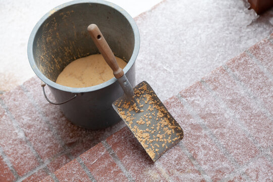 Small spatula and bucket of sand stands on snowy steps