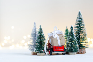 Red toy car truck carrying of Christmas gift boxes aginst netural background. Holiday greeting...