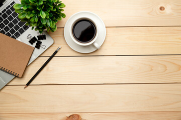 Top view office table desk. Workspace with blank, office supplies,Laptop, pencil, green leaf, and coffee cup on wood background.