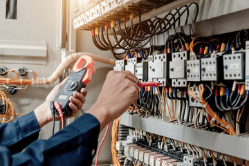 Fototapeta Electrician engineer uses a multimeter to test the electrical installation and power line current in an electrical system control cabinet. obraz