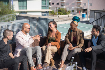 Relaxed business people on terrace roof party. Men and women in formal clothes sitting on rattan sofas around table with appetizers and champagne. Teambuilding, party concept