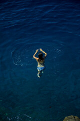 Laguna młoda kobieta z długimi włosami utrzymuje się na powierzchni  lazurowej wody - obrazy, fototapety, plakaty