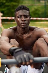 Young black man doing crunches outdoors. He is in a park.