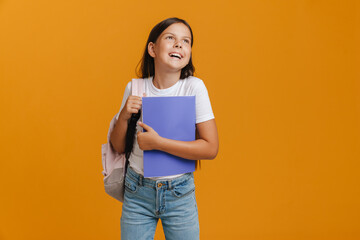 White brunette girl laughing while posing with backpack and exercise book