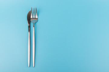 A fork and knife on blue background. Flat lay Dishes for breakfast, lunch or dinner.