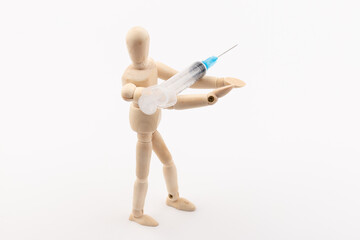 wooden mannequin with syringe against white background