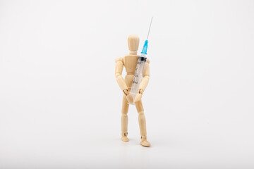wooden mannequin with syringe against white background