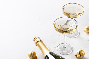 Festive New Year champagne and Christmas gold baubles on white background with copy space. Close up.