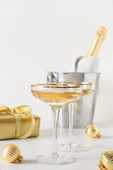 New Year champagne and Christmas gold gift and baubles on white background. Vertical format. Close up.