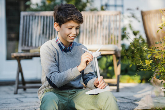 Smiling boy playing with turbine model at backyard