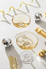 New Year champagne and Christmas silver disco balls on white background. Vertical format. Festive greeting card. Close up.