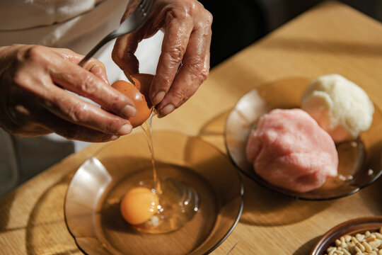 Woman breaking egg in bowl at kitchen