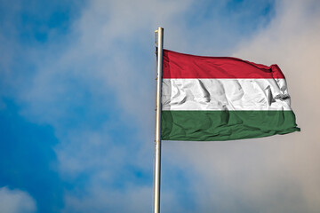 A Flag of Hungary an flying on a Flagpole against the Sky