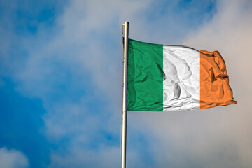 A Flag of Irland an flying on a Flagpole against the Sky