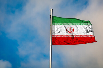 A Flag of Iran flying on a Flagpole against the Sky