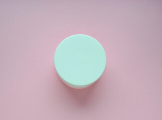 Round packaging of cream. Jar of cream isolated on pink background. Flat lay, top view, copy space.