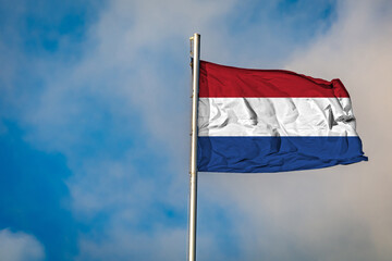 A Flag of the Netherlands flying on a Flagpole against the Sky