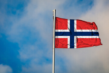 A Flag of Norway flying on a Flagpole against the Sky